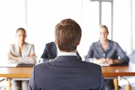 young man sitting before an interview panel of three