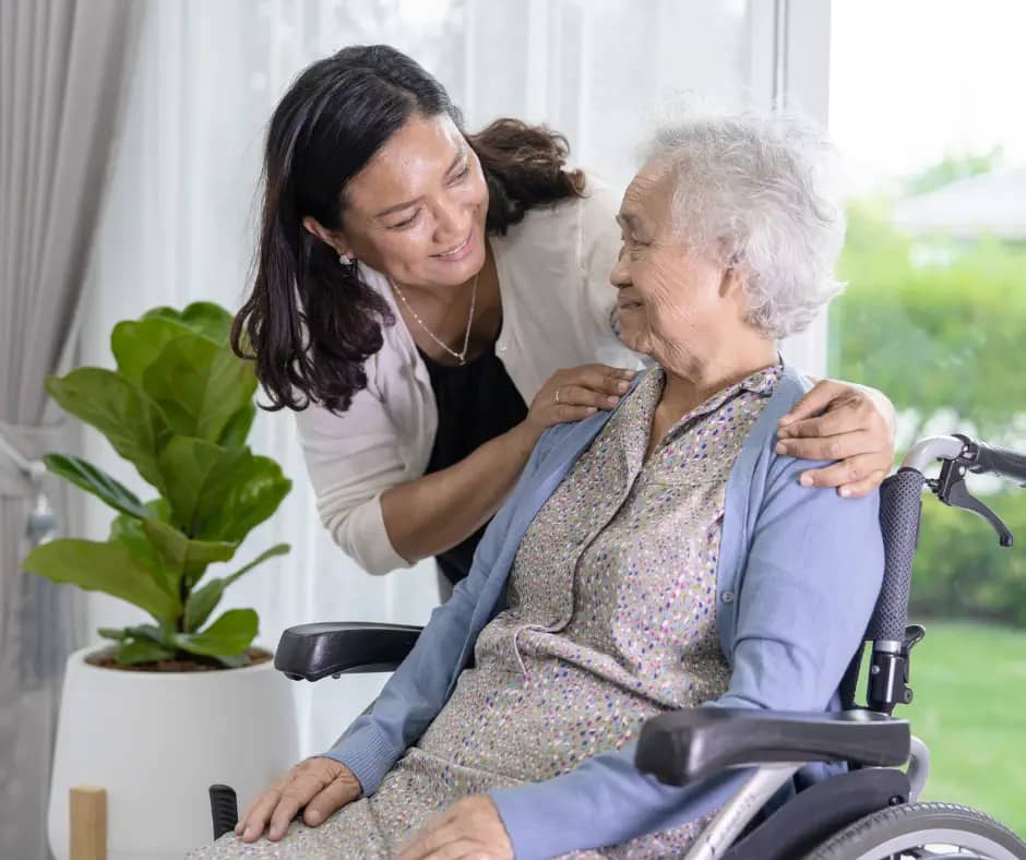 smiling aged care worker looking after smiling elderly woman in a wheelchair