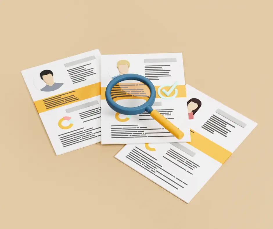 picture of 3 CVs sprawled out on a table with a magnifying glass