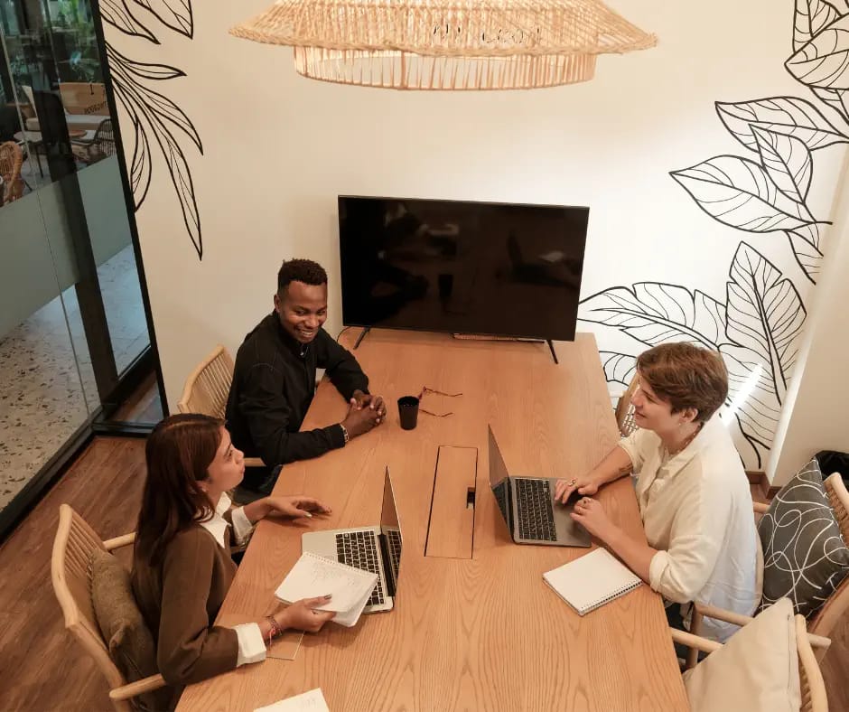 three professionals including 2 women with laptops sitting around a table offering outplacement support